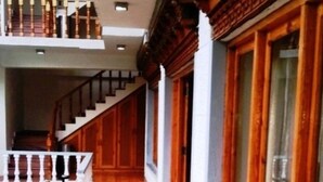 A corridor with wooden flooring, a staircase, and a white railing. - TIH Hotel Kidar, Leh (Leh)
