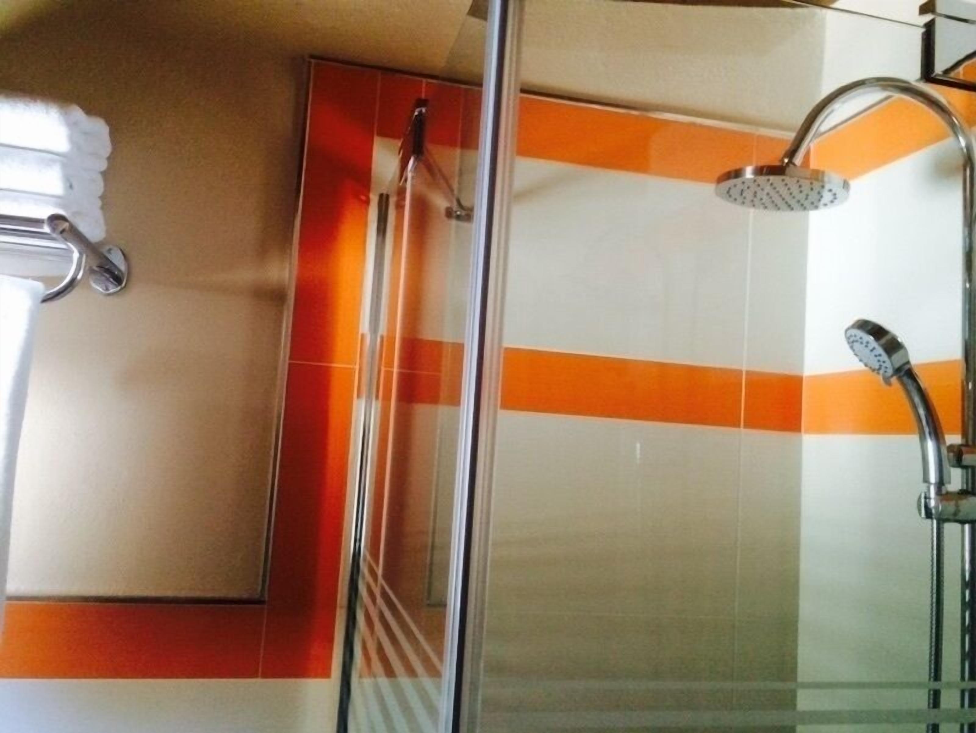 Ein Badezimmer mit Duschkabine aus Glas, Handtuchhalter und Spiegel.