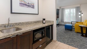 A modern kitchen with granite countertops, a built-in microwave, and a dishwasher. There is a framed picture on the wall and a window with curtains. - Hampton Inn & Suites Pensacola/Gulf Breeze (Gulf Breeze)