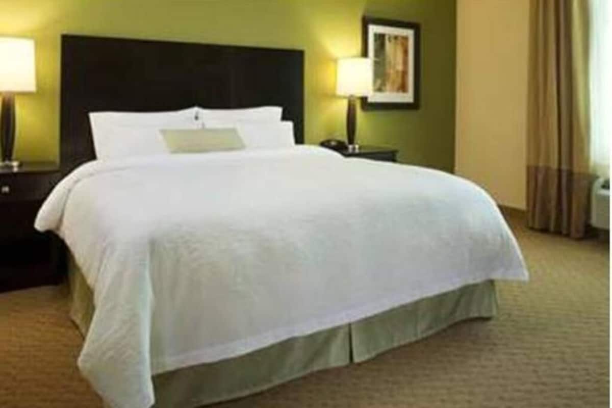 A hotel room with a large bed, a nightstand with a lamp, and a wall-mounted picture.