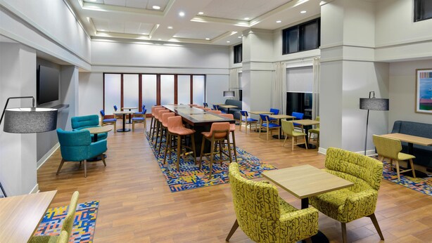 A spacious hotel lobby with a long communal table, several seating areas, and a modern ceiling design. - Hampton Inn & Suites Pensacola/Gulf Breeze (Gulf Breeze)