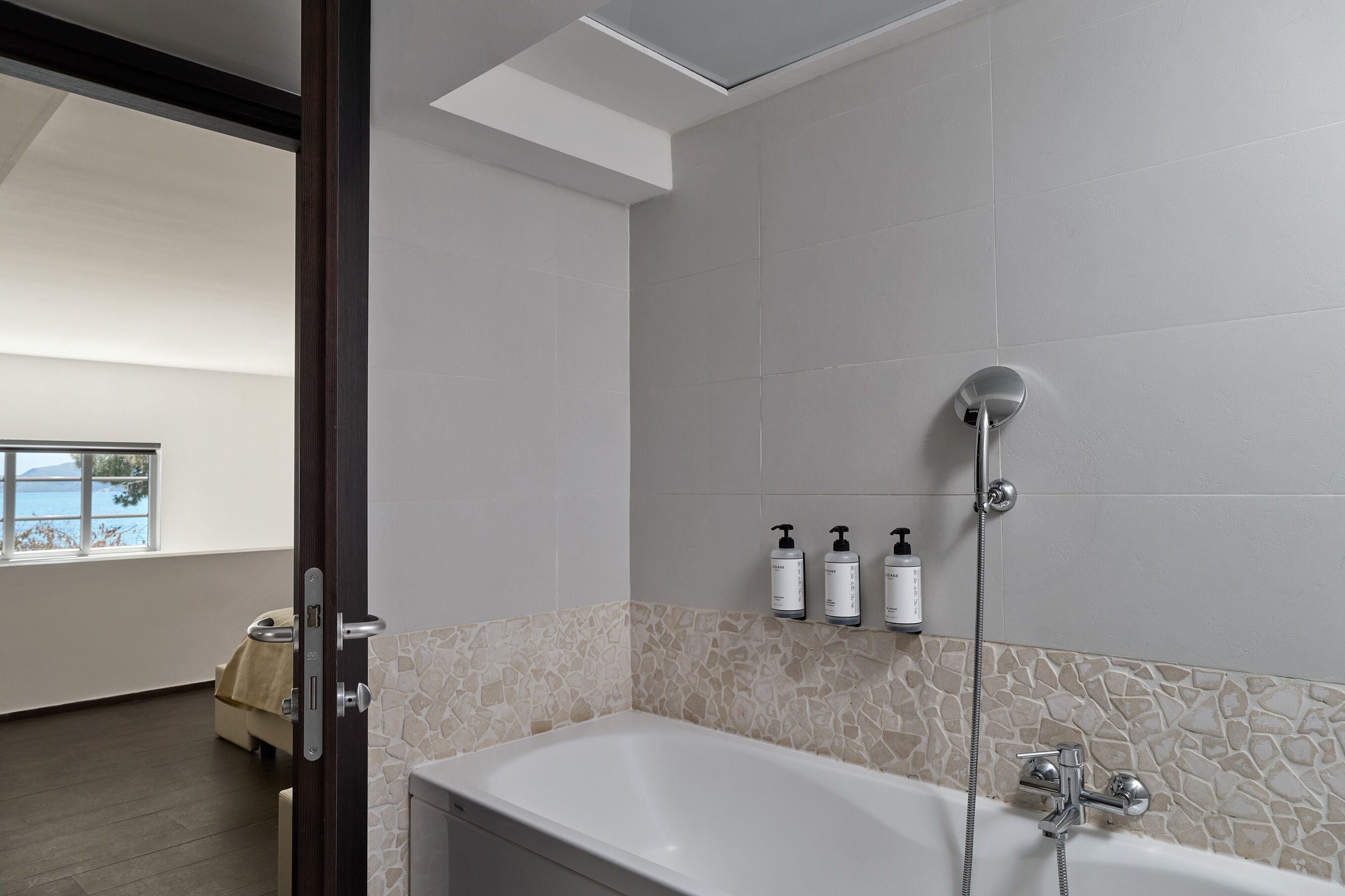 Et moderne badeværelse med badekar, brusebad og toiletartikler på en hylde.