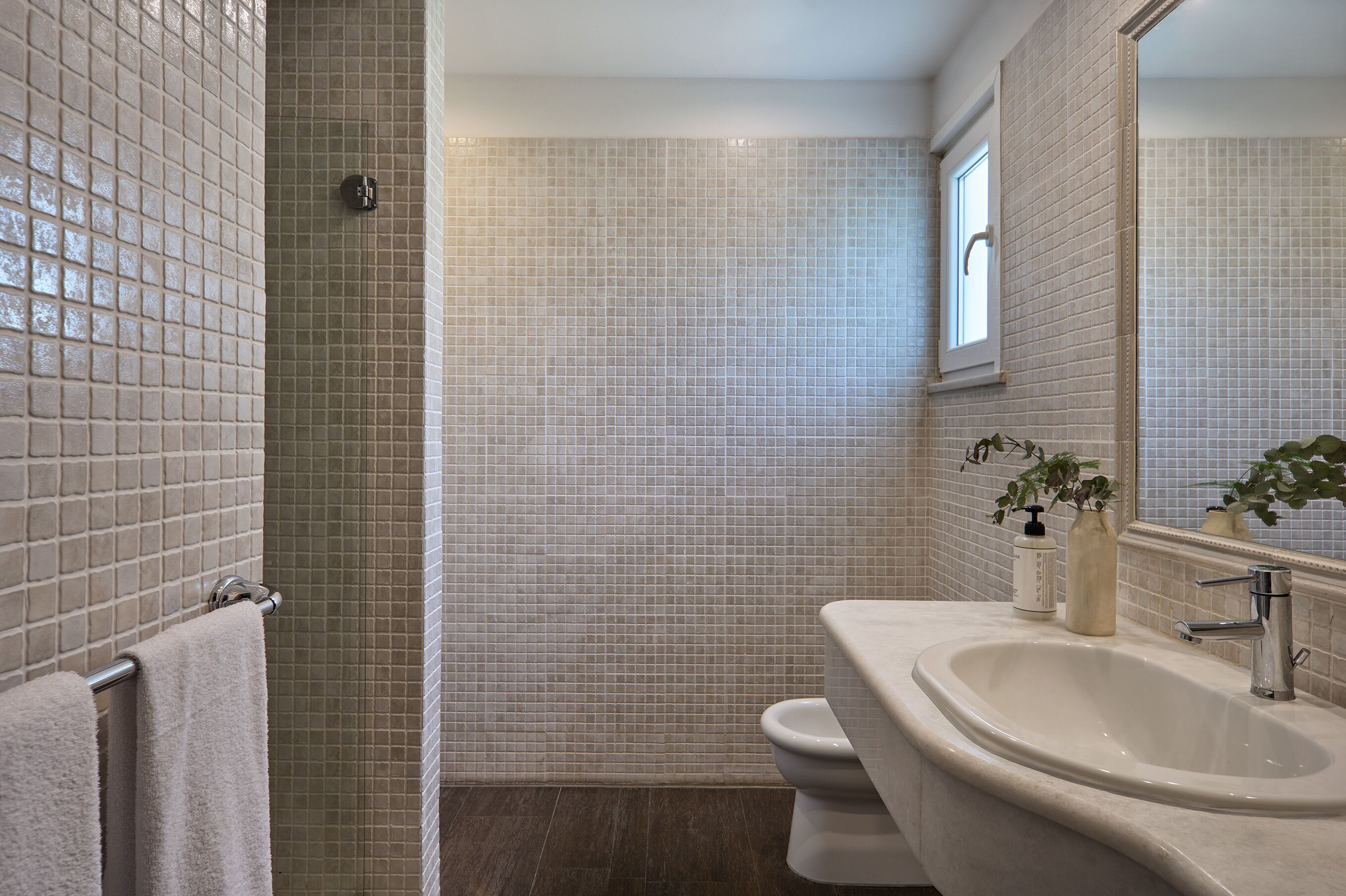 A bathroom with a tiled shower, a sink, and a toilet.