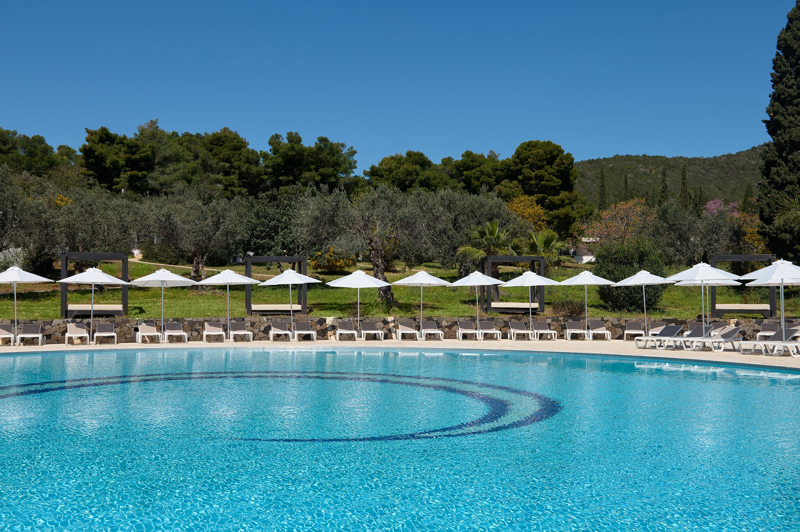 Una piscina techada, una piscina al aire libre, sombrillas