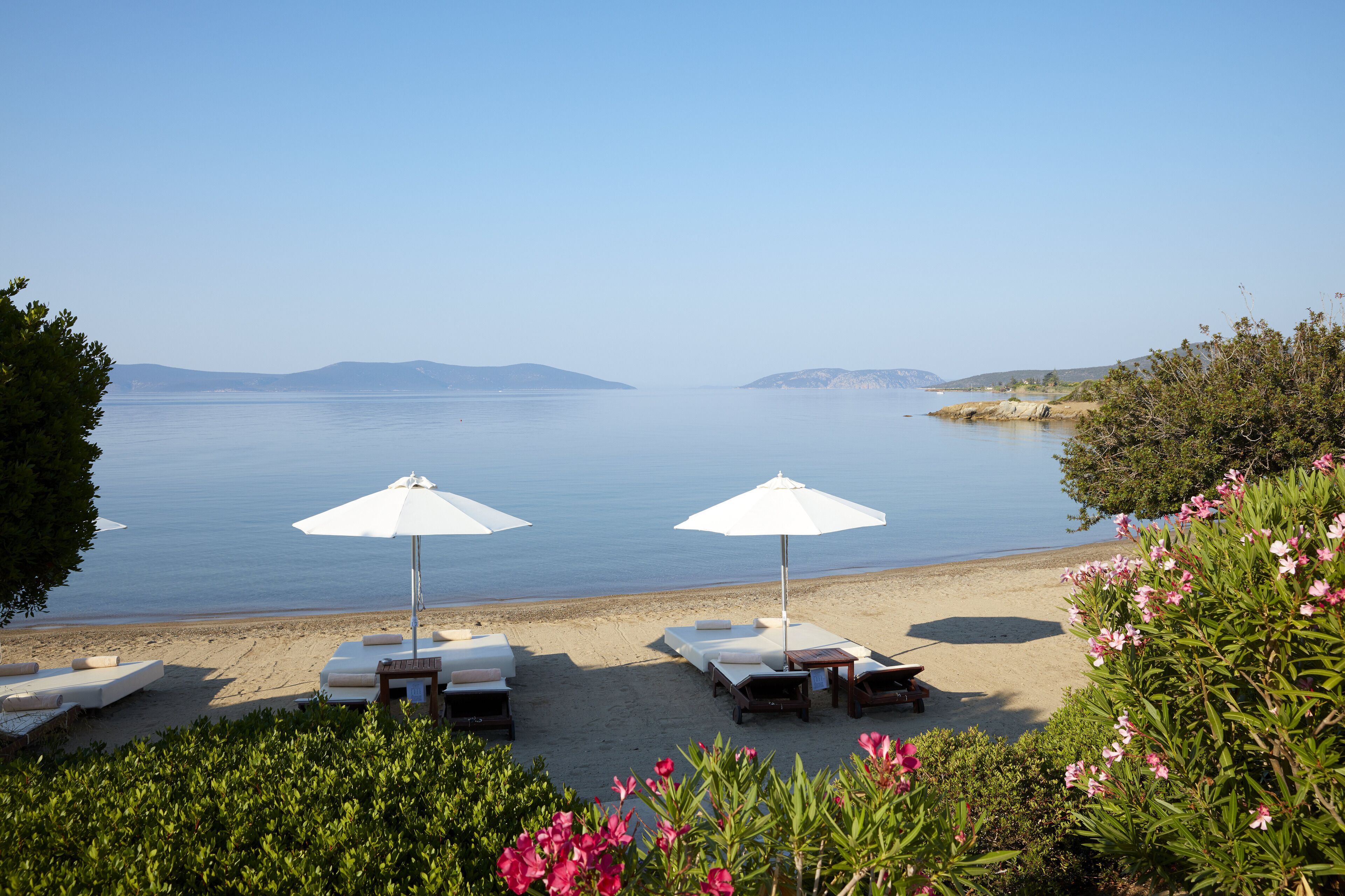På stranden, hvit sand, solsenger og parasoller