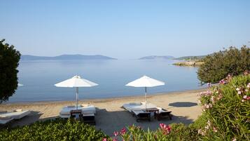 Na praia, areia branca, espreguiçadeiras, guarda-sóis