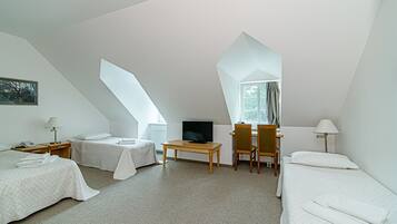 A modern, well-lit room with two beds, a desk, a television, and a window with curtains.
