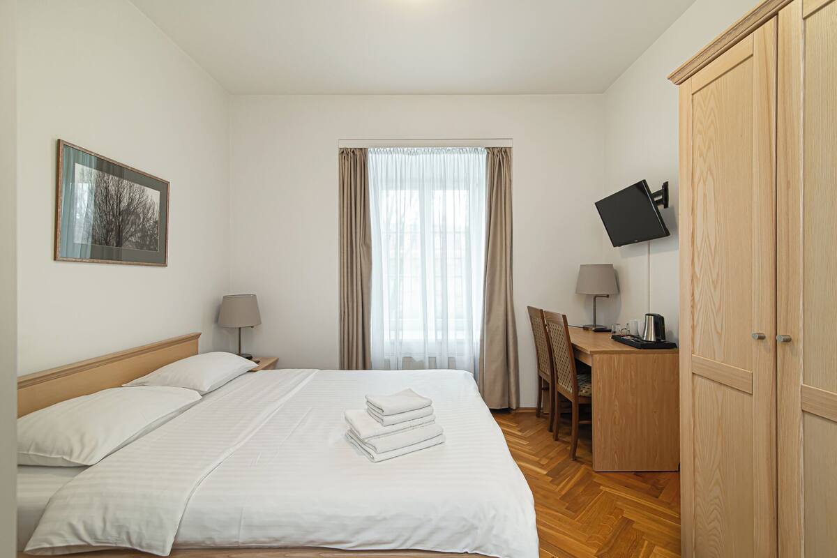 Une chambre d’hôtel comprenant un lit, un bureau avec une chaise, une télévision et une armoire.