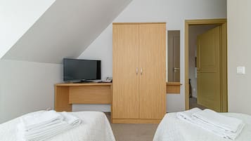 Ein Schlafzimmer mit einem Bett, einem Fernseher, einem Kleiderschrank und einer Tür.