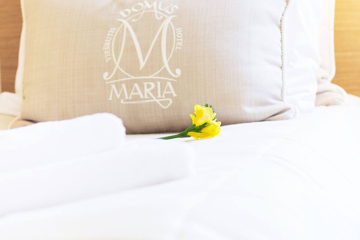 Un lit bien fait, avec un oreiller orné d’un monogramme et du nom « Maria ».