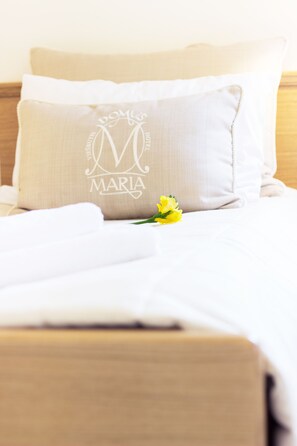 A neatly made bed with a pillow featuring a monogram and the name "Maria".