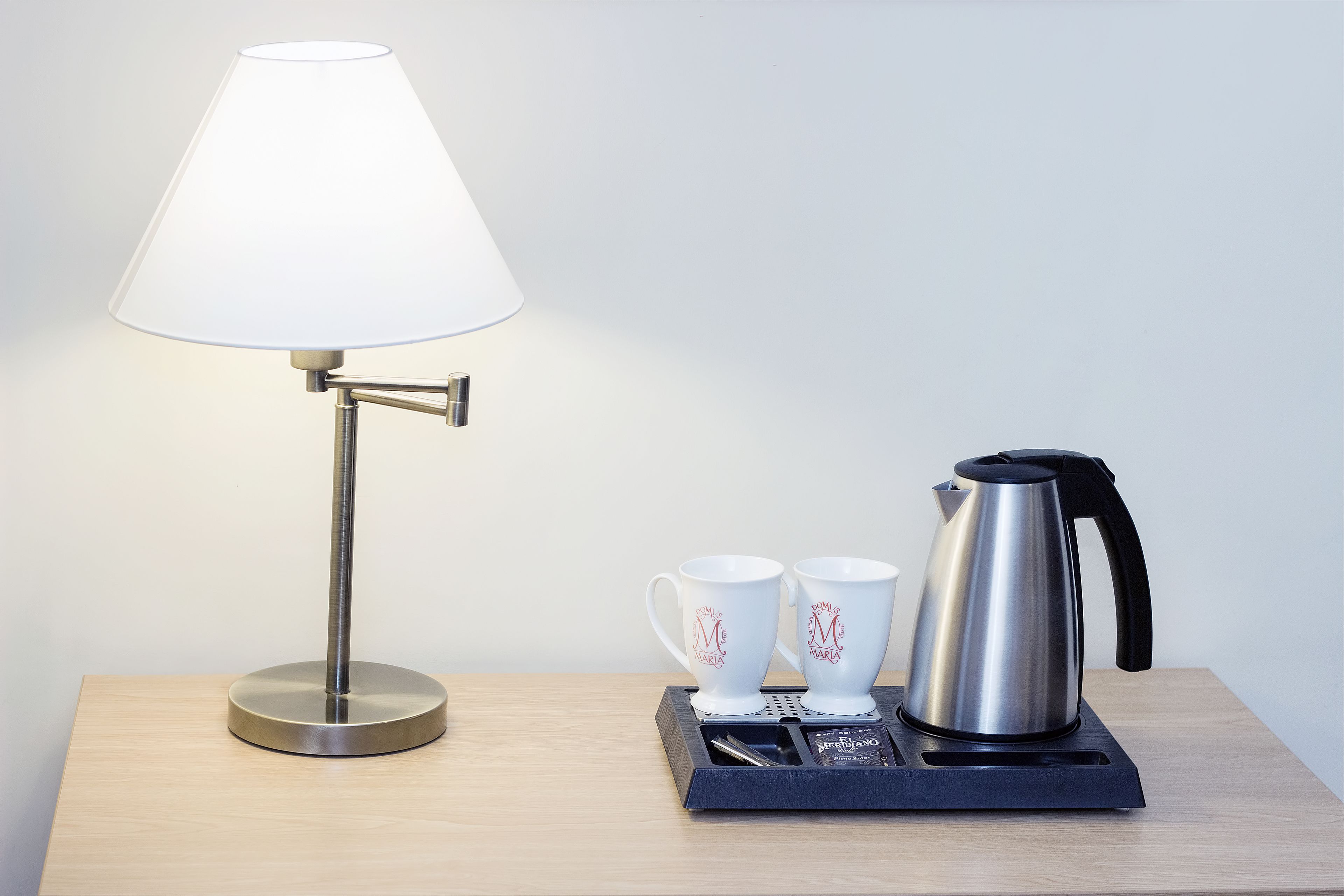 A table with a lamp, two mugs, and a kettle.
