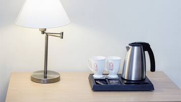A table with a lamp, two mugs, and a kettle.