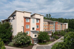 A multi-story hotel with a beige and red exterior, multiple windows, and a parking area in front. - Residence Inn by Marriott Columbia Northwest/Harbison (Irmo)