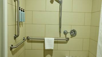 A shower area with grab bars, a towel rack, and a handheld showerhead.