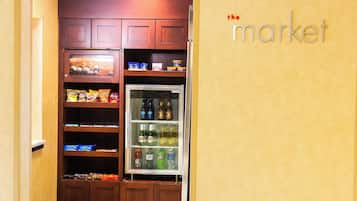 Una cocina con armarios de madera, un refrigerador lleno de bebidas y un estante con aperitivos.