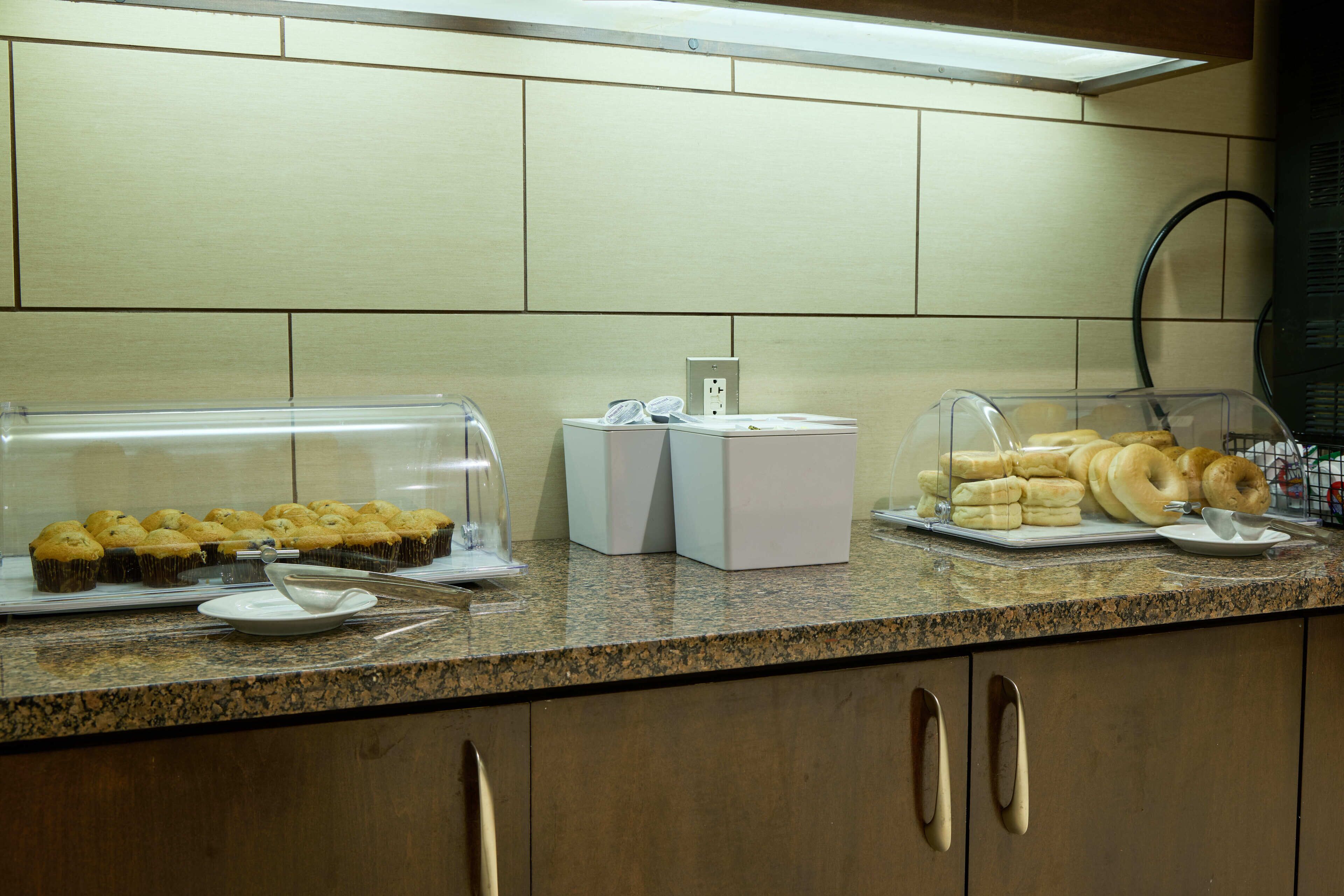 Una barra de buffet con diversas opciones de panadería exhibidas en recipientes transparentes.