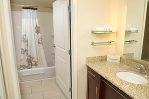 A bathroom with a shower curtain, a bathtub, a sink, and a mirror. - Residence Inn by Marriott Columbia Northwest/Harbison (Irmo)