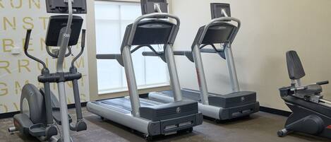 A gym with treadmills, an elliptical, and a bench.
