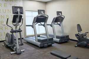 Un gimnasio con cintas de correr, elíptica y banco.