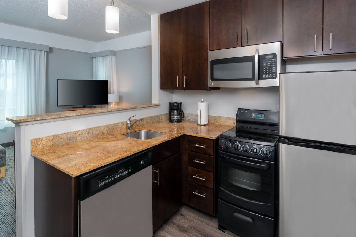 A compact kitchen with a dishwasher, microwave, stove, and refrigerator.