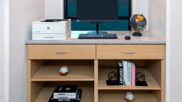Um espaço de trabalho com um computador de mesa, impressora HP, teclado e um globo. Há livros nas prateleiras e uma pequena planta na mesa.
