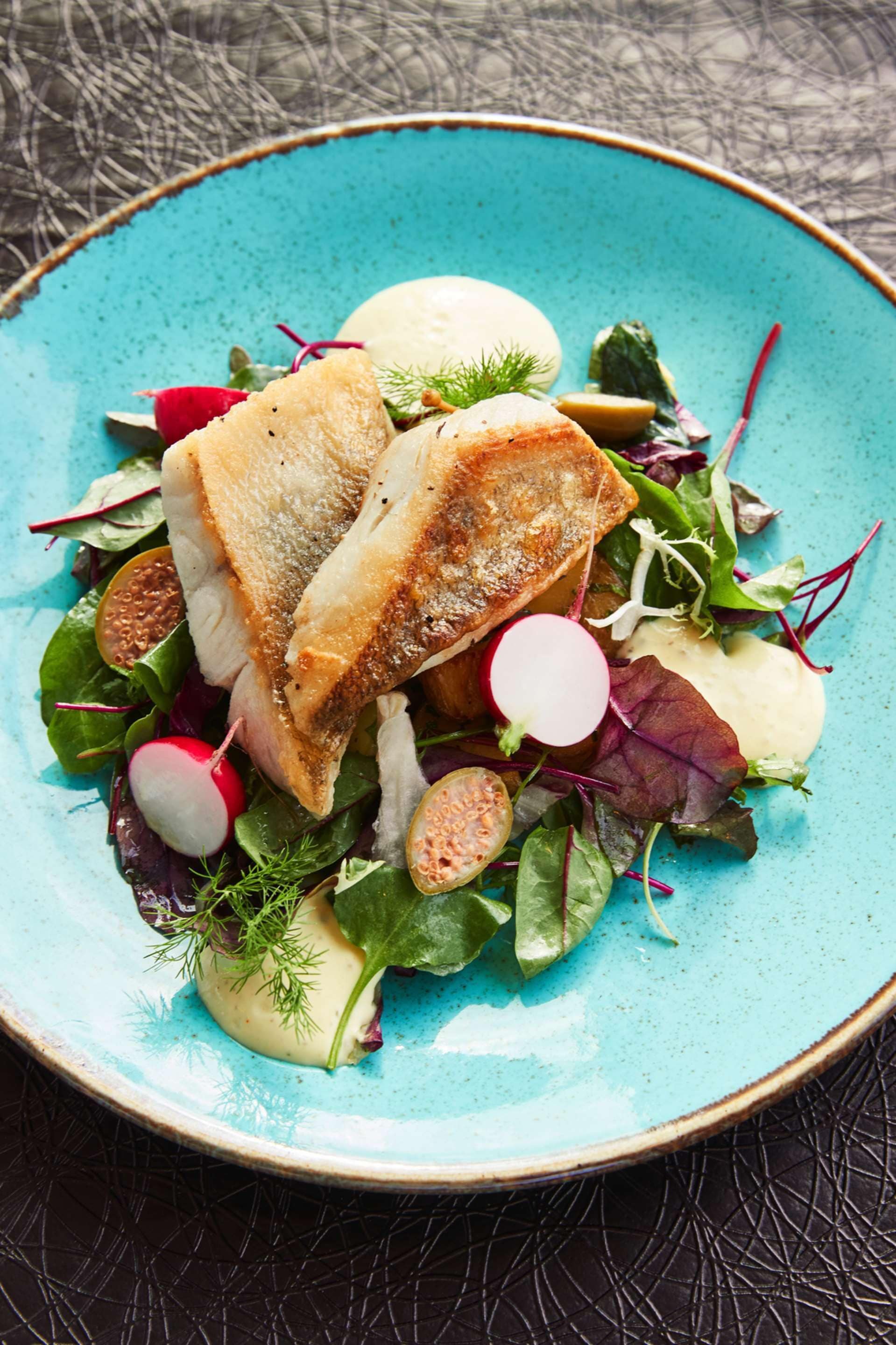 A plate of food with fish, radishes, and greens.