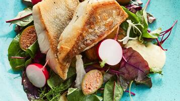A plate of food with fish, radishes, and greens.