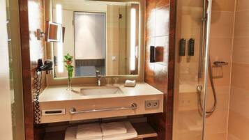 A modern bathroom with a large mirror, sink, and shower.