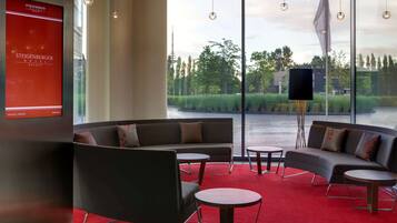 A modern hotel lobby with a red carpet, a sofa, and two small tables.