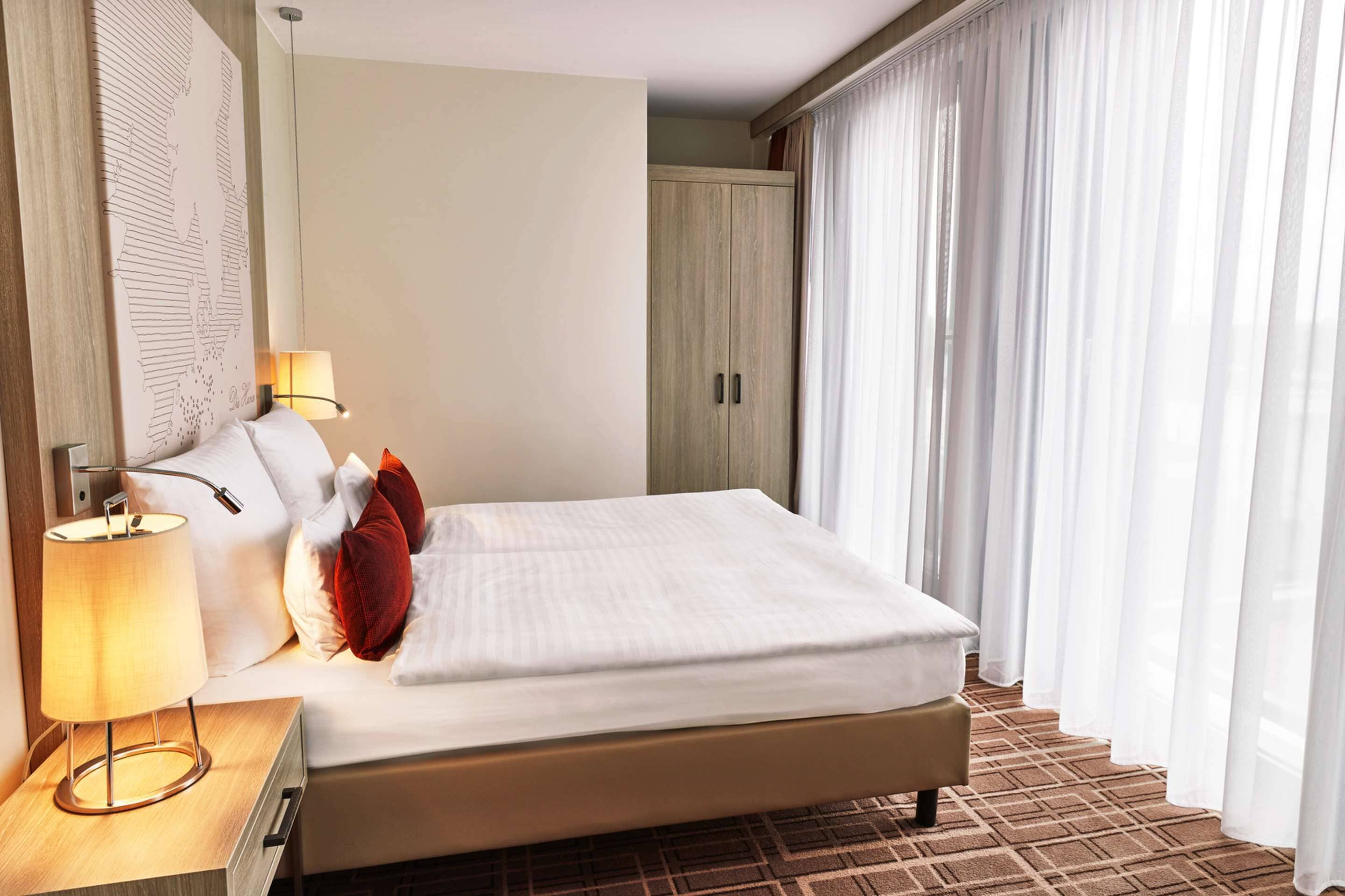 Ein Hotelzimmer mit Bett, Nachttisch mit Lampe, einer Karte an der Wand und einem Kleiderschrank.