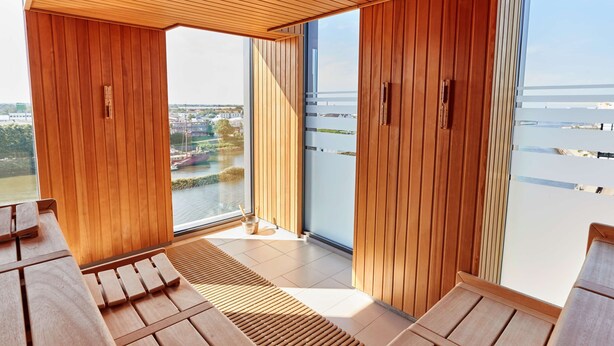 Una habitación moderna con paneles de madera, ventanas amplias y vista a una masa de agua.
