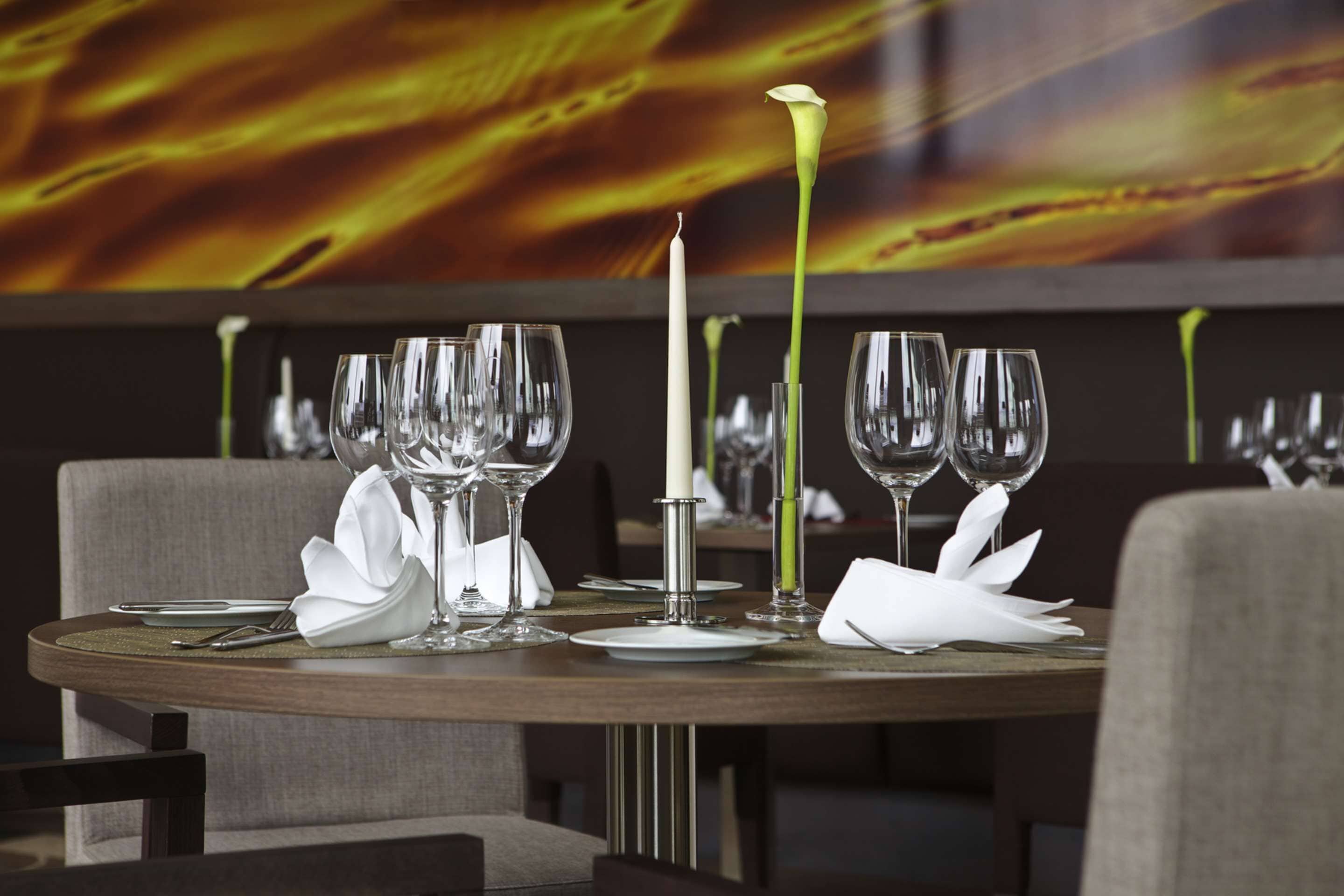 A dining table set with multiple wine glasses, a candle, and white napkins.