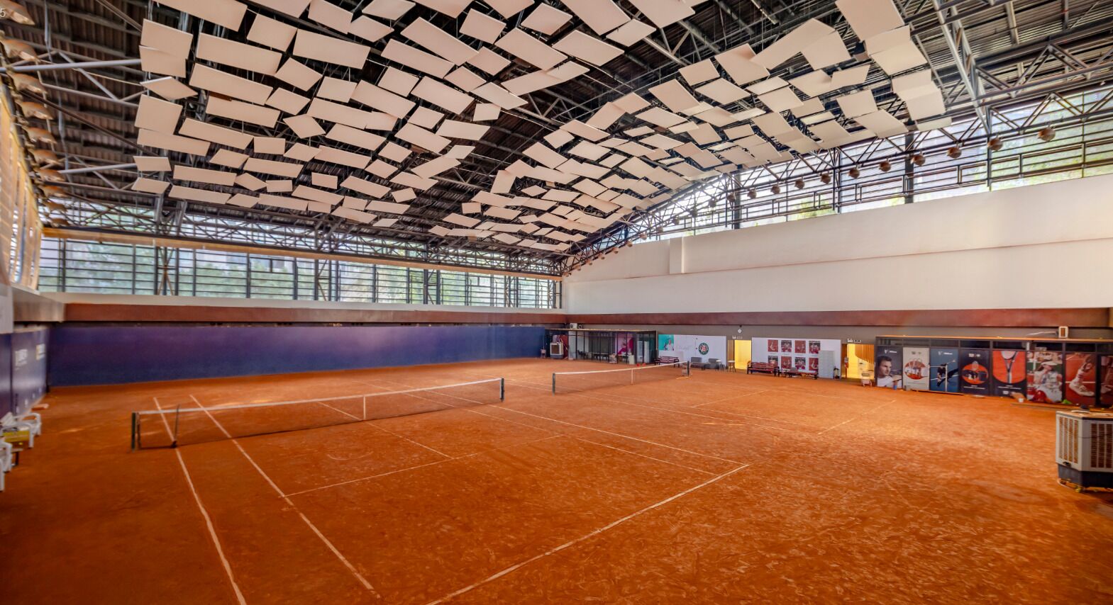 Una palestra al coperto con campo da tennis, soffitto alto e rete al centro.