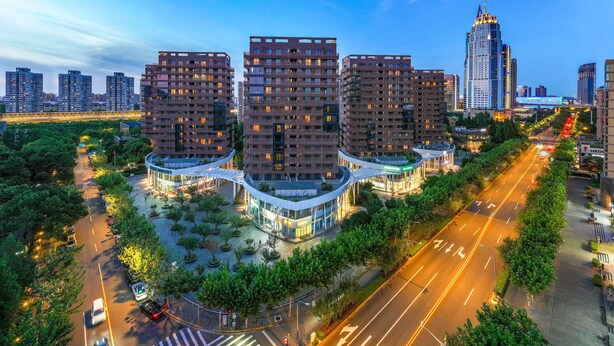 A modern urban area with high-rise residential buildings, a well-maintained road, and a pedestrian walkway.