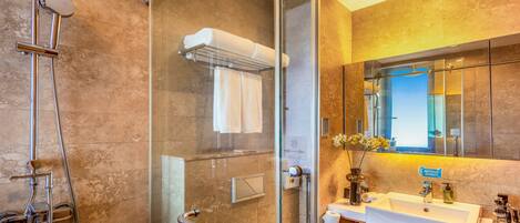 A modern bathroom with a glass-enclosed shower, a toilet, a sink with a mirror, and a trash can.