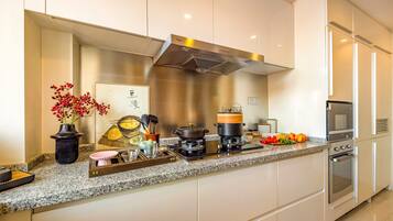 Una cocina moderna con encimera de granito, electrodomésticos de acero inoxidable y un florero decorativo con bayas rojas.