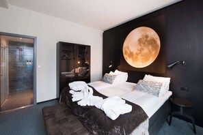 A modern hotel room with a large bed, a round wall clock, and a shower area.
