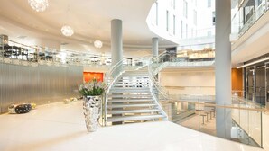 A spacious, modern interior with a central staircase, glass railings, and contemporary lighting fixtures.