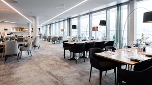 A modern dining area with long tables, chairs, and pendant lighting.