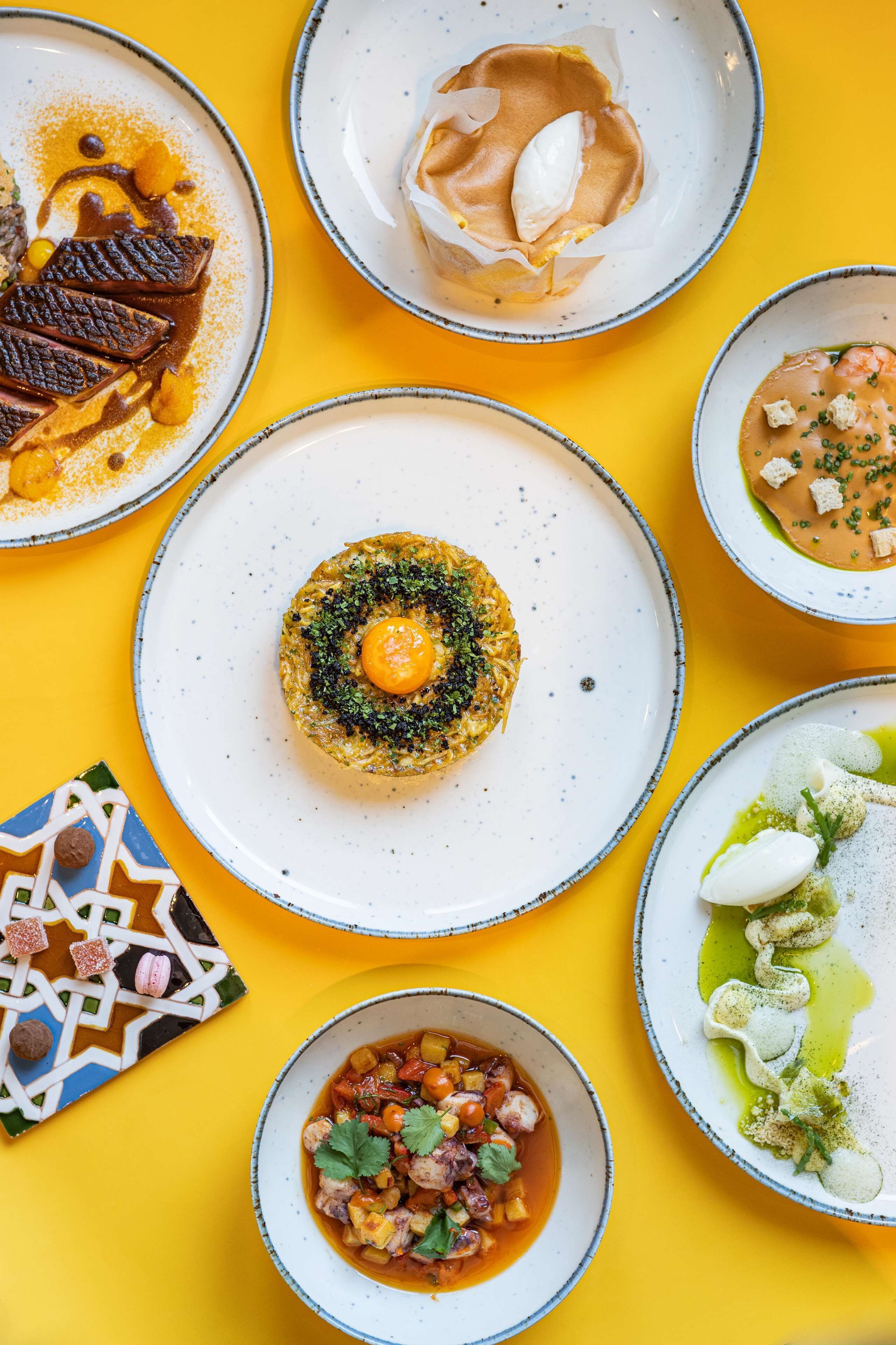 Diversos platos con comida sobre una superficie amarilla.