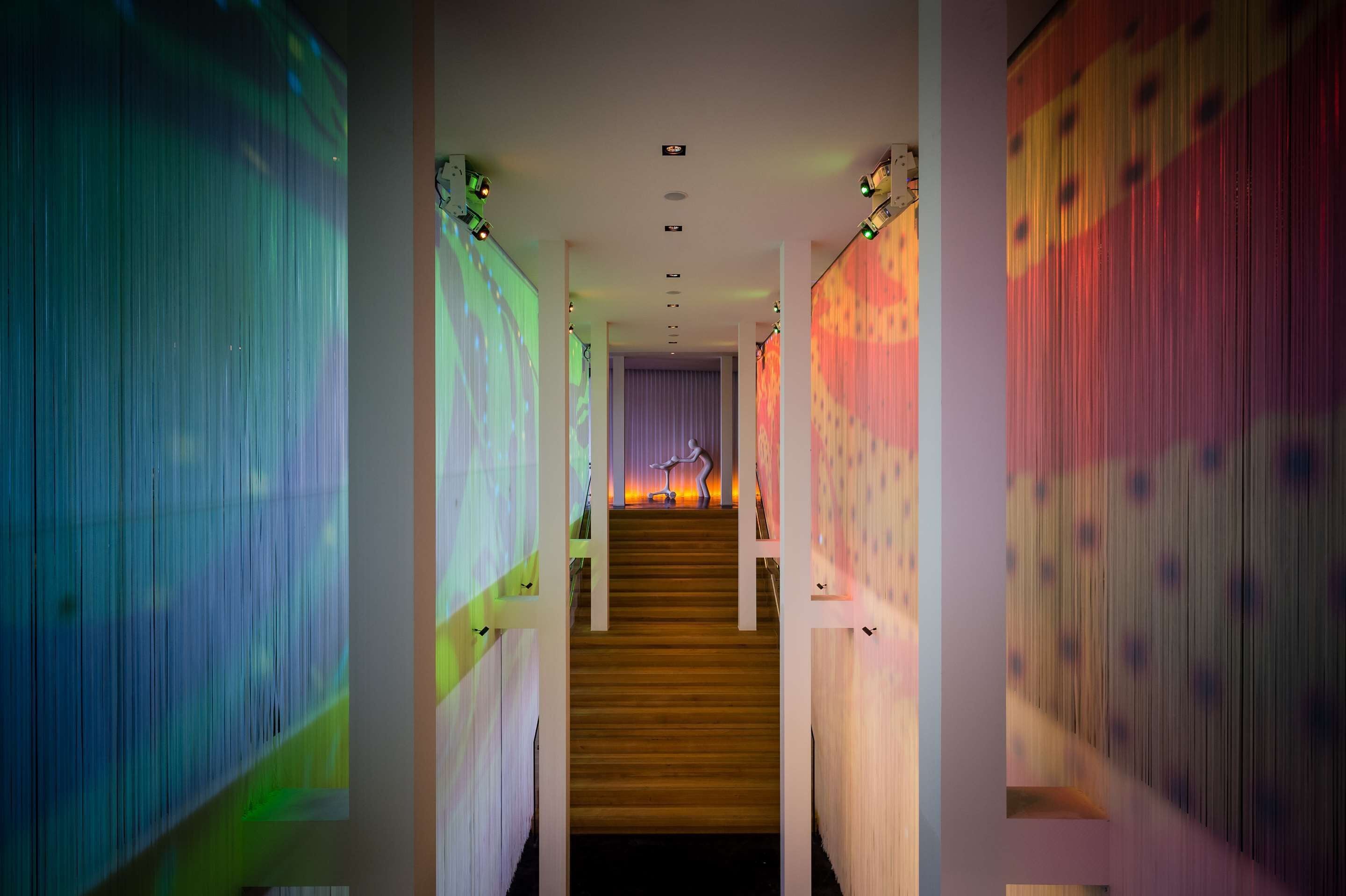 A staircase with a person at the top, flanked by walls with colorful projections.