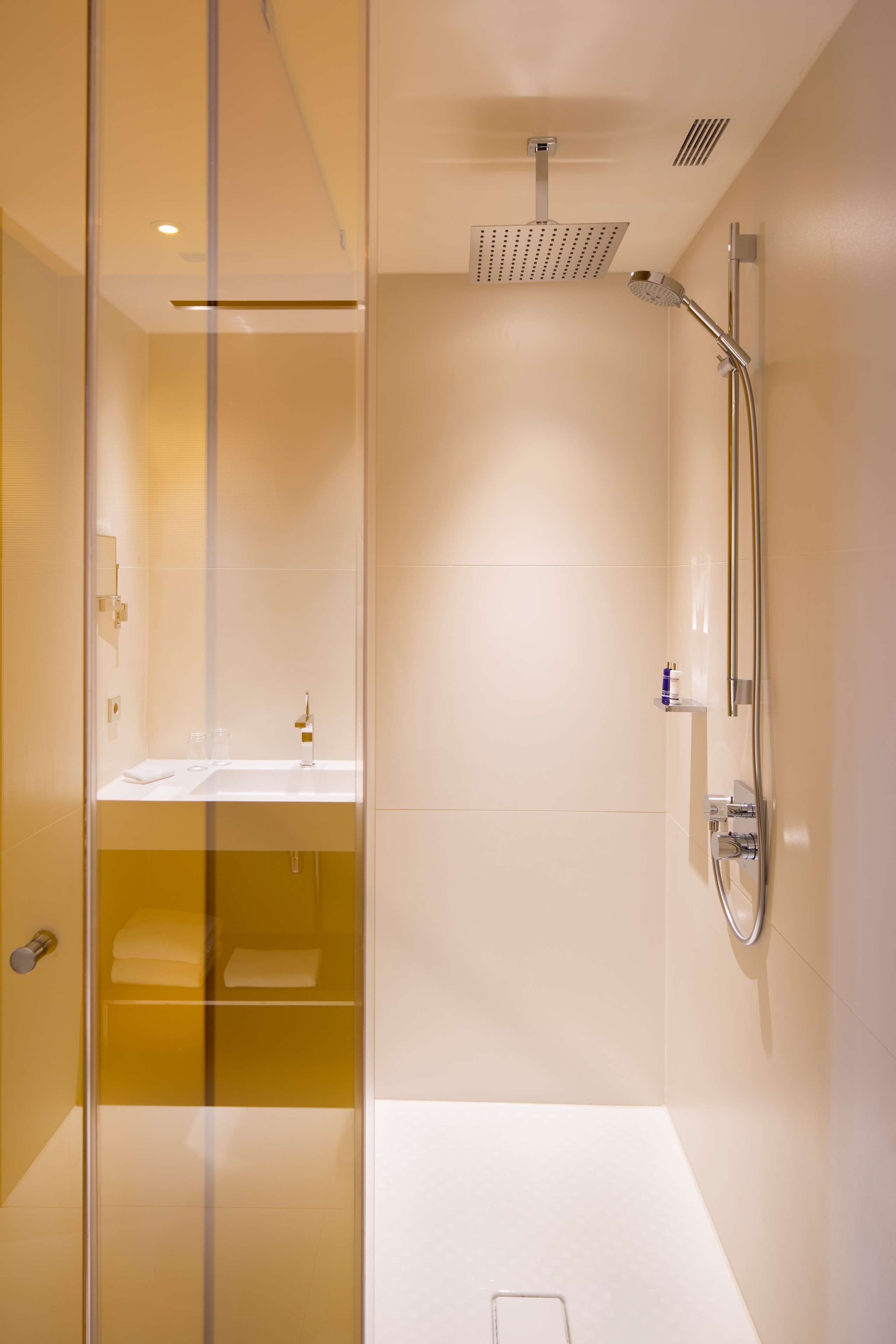 Ein modernes Badezimmer mit Duschkabine aus Glas, einem weißen Waschbecken und einer Handbrause.