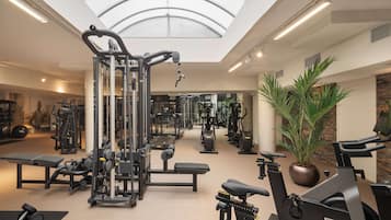 Un gimnasio con equipos de ejercicio variados, un tragaluz y una planta en maceta.