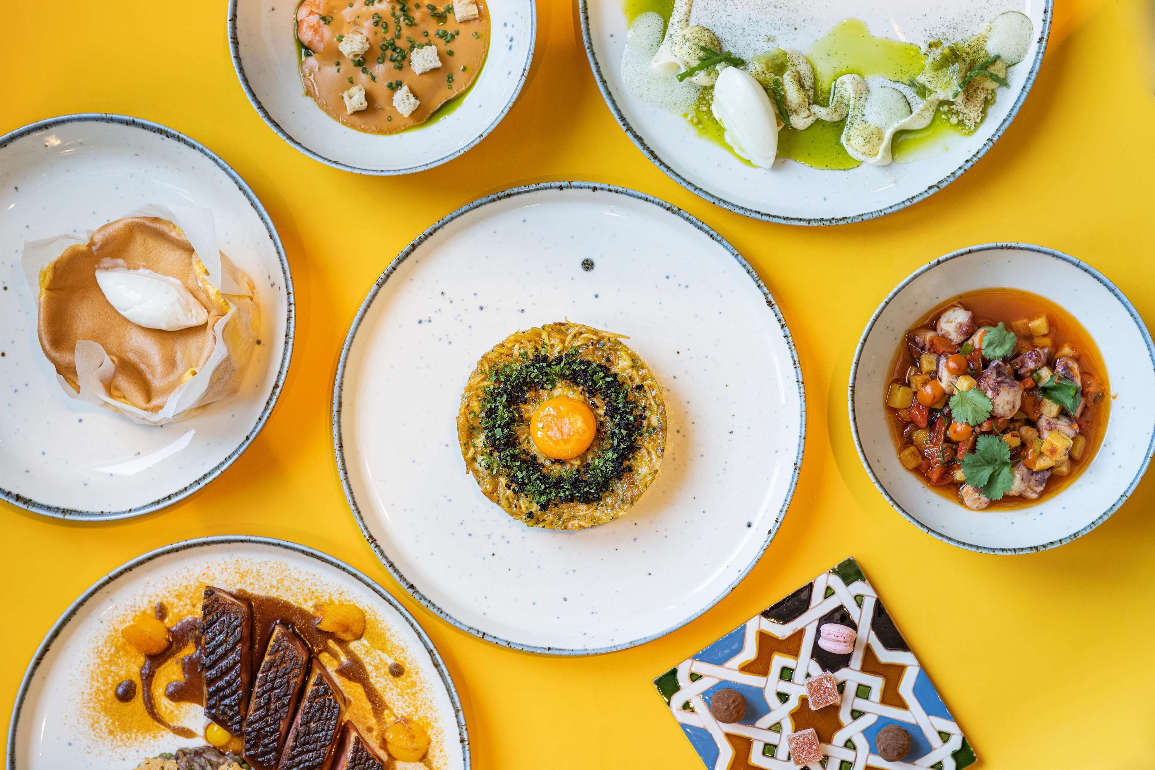 A variety of dishes on plates with a yellow background.