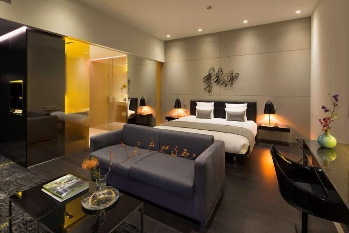 Ein modernes Hotelzimmer mit Bett, Nachttischen, einer Couch und einem Couchtisch.