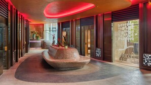 Un hall d’entrée moderne doté d’un élément décoratif central en eau, de grandes fenêtres et d’un comptoir d’accueil.