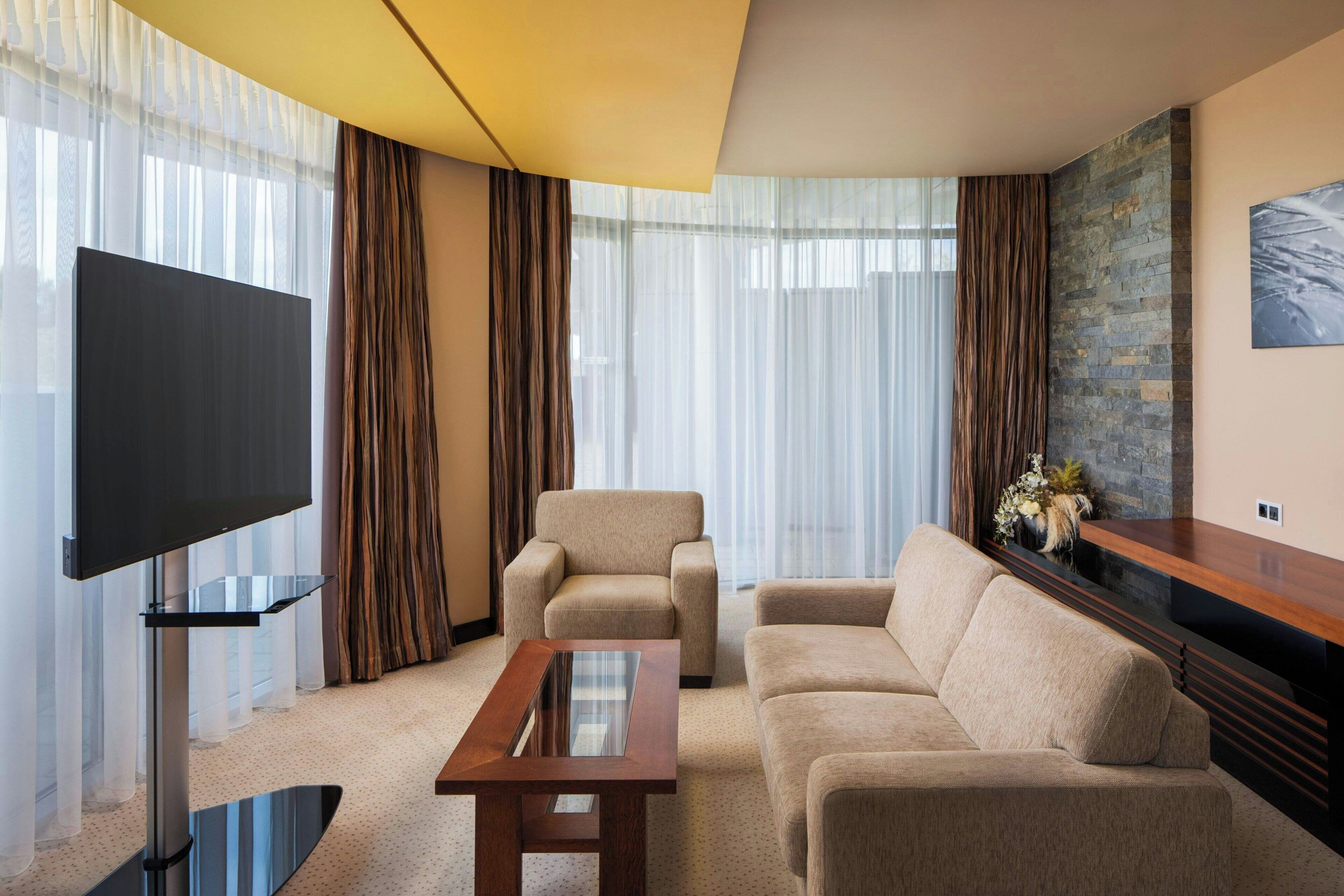 Una sala de estar moderna con un televisor de pantalla plana, dos sofás, una mesa de centro y una pared decorativa de piedra.