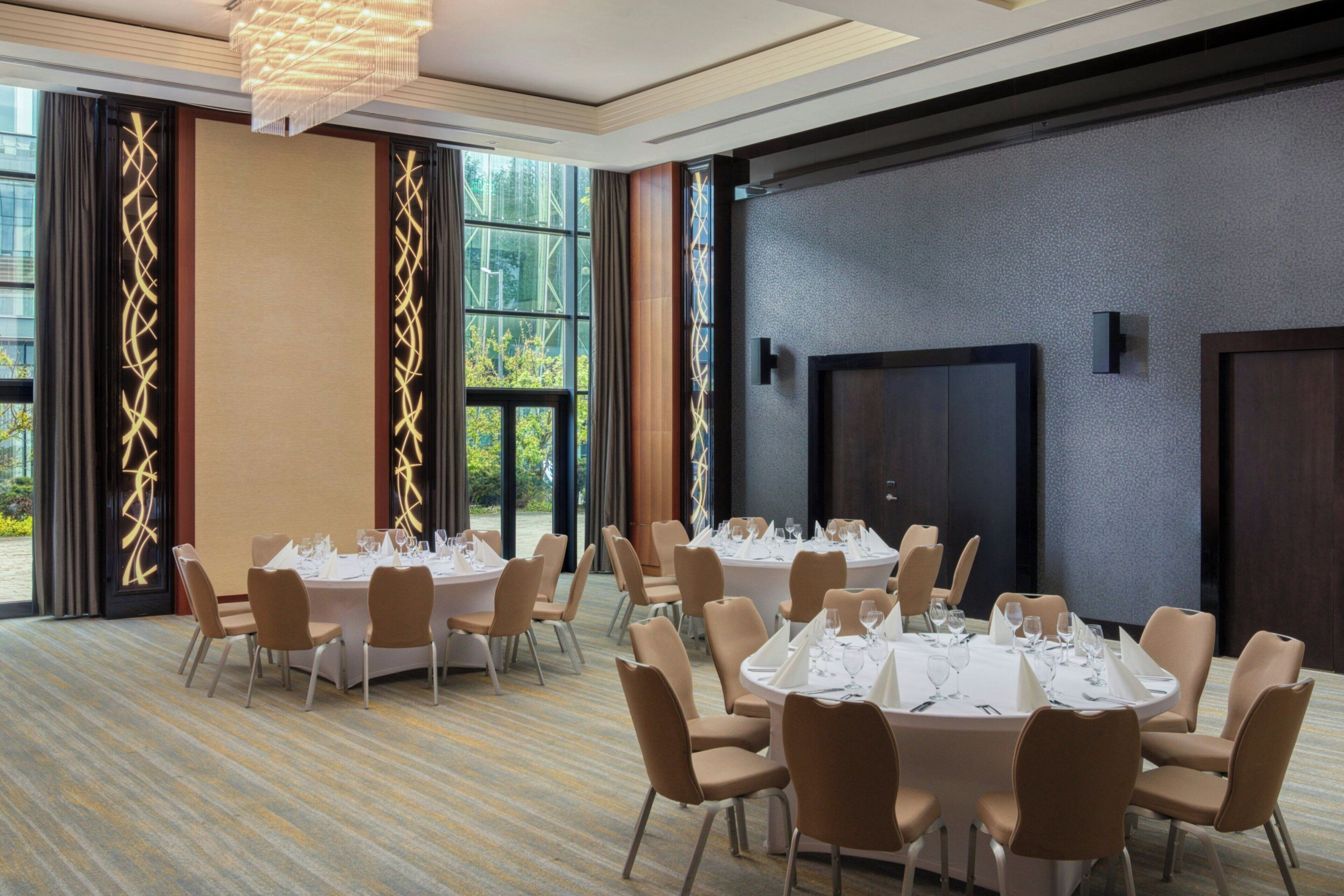 A conference room with round tables, chairs, and a large window.