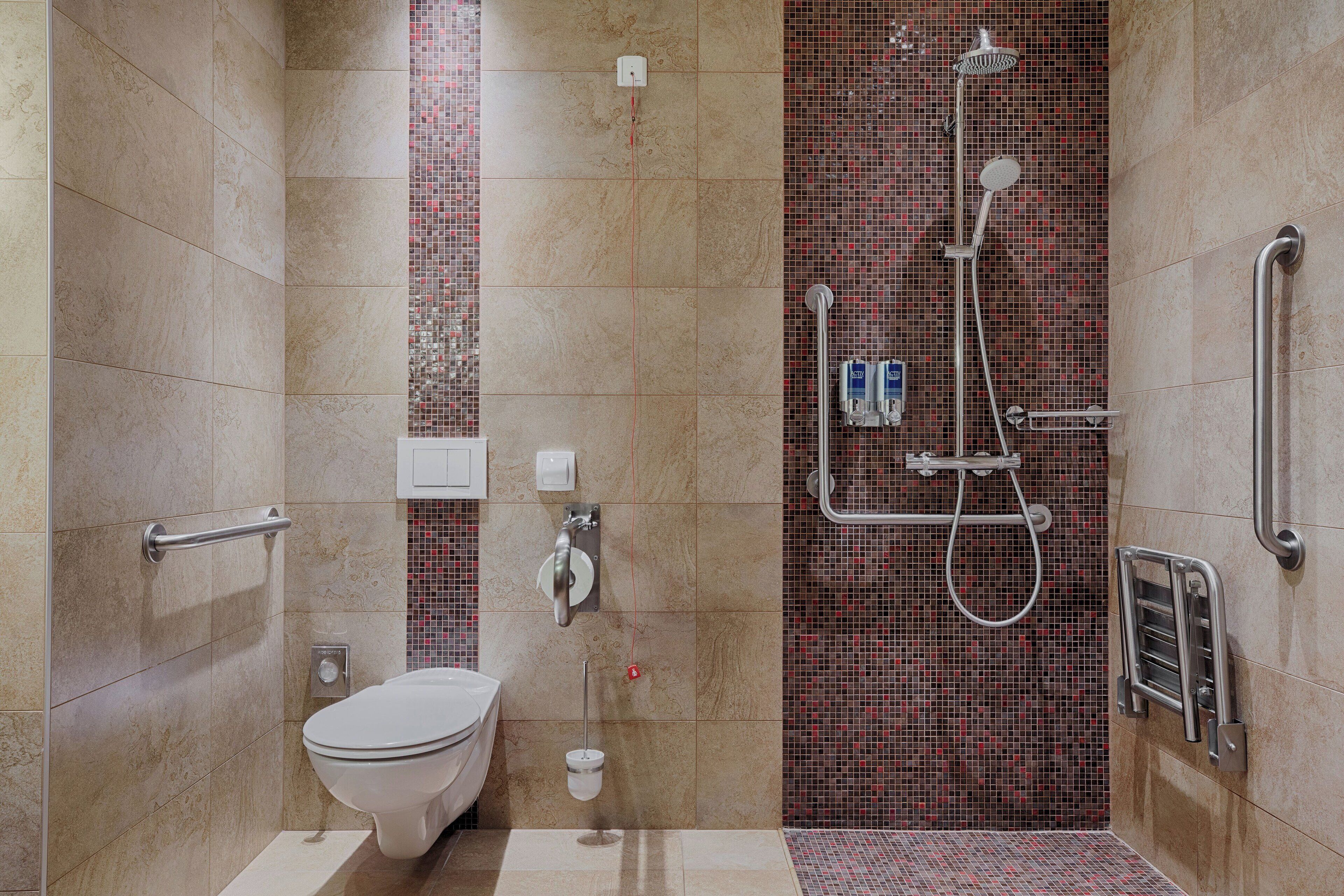 Een moderne badkamer met toilet, hygiëneschuimer en inloopdouche.